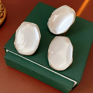 Detail of silver oval resin earrings with white luster on a green jewelry box