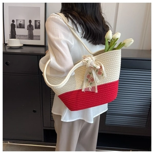 Detail of red and white woven tote bag with floral ribbon held by a model