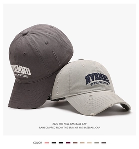 Close-up of distressed cotton baseball caps with NVRMND embroidery and frayed edges