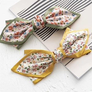 Detailed view of floral satin bow hair clips in green and yellow on a magazine