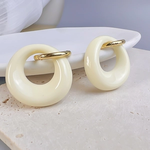 Detailed close-up of cream oval resin hoops with 18K gold-plated metal clasp earrings