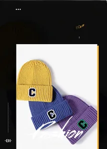 Dettaglio dei berretti in maglia con patch C in giallo, blu e viola