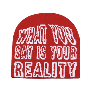 Detail of red knit beanie featuring white jacquard text pattern with a street style aesthetic