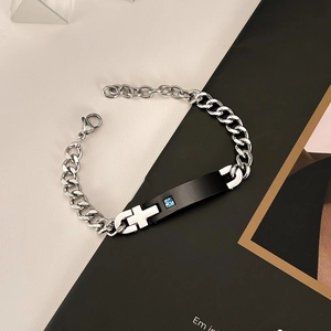 Detail of silver stainless steel chain with black bar, cross pattern and blue stone