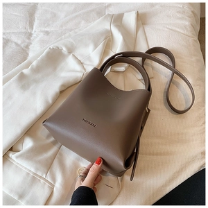 Detailed view of a brown vintage leather bucket bag styled on a white blazer