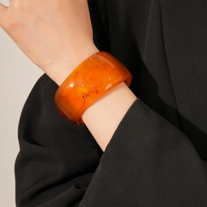 Close-up of translucent amber resin bangle showing natural swirled marble texture on wrist
