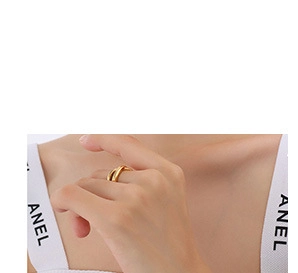 Gros plan d'une bague croisée dorée portée par un mannequin sur fond blanc épuré