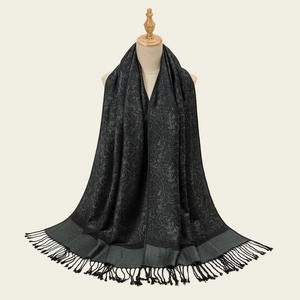 Elegant black paisley jacquard scarf with tassels displayed on a wooden mannequin