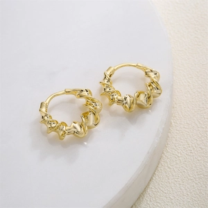 Eleganti orecchini a cerchio attorcigliati in oro 14K su supporto in marmo bianco