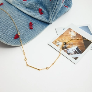 Détail macro du collier en acier inoxydable doré 18K avec zircons sur un chapeau