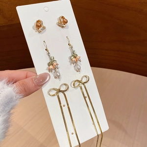 Detailed close-up of golden floral pearl earrings and bow tassel earring set for women