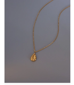 Macro view of gold teardrop necklace featuring unique lava texture and fine cable chain