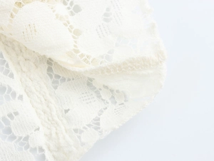 Close-up of white French lace fabric texture with elegant hollow patterns and sewing details