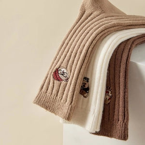 Macro shot of knitted socks showing bear embroidery and ribbed texture in earthy tones