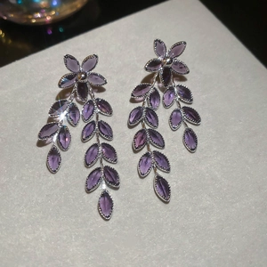 Detailansicht der silbernen Blumenohrringe mit lila Kristallblüten und Blattdesign