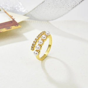 Detail of adjustable gold ring featuring four round pearls and sparkling zircon accents