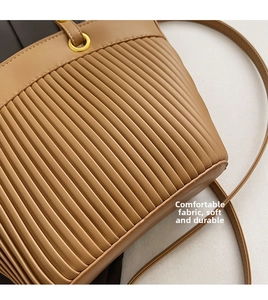 Close-up of pleated caramel leather texture and golden ring hardware on large tote bag