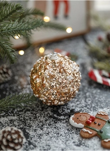 Macro shot of 8cm gold Christmas ball with sequins and white pearls on snow