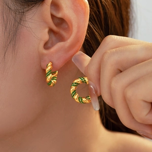 Elegant gold-plated U-shaped twist earrings with emerald green zircon stones on model