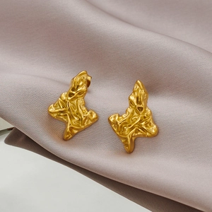Vue macro de boucles d'oreilles triangles dorées avec texture métallique froissée