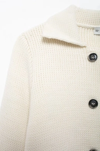 Gros plan d'un cardigan en maille crème avec col classique et détails de boutons noirs