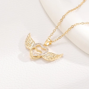 Macro detail of gold angel wing pendant with intertwined hearts and sparkling zircon stones