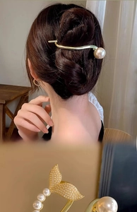 Detail of gold pearl hair clips featuring fish tail design and minimalist bar style