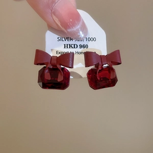 Detail of red zircon earrings with bow decoration and 925 silver needle hallmark