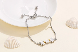 Detail of adjustable silver and gold heart tulip bracelet on a soft beige background