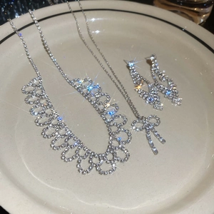 Macro detail of luxury bow jewelry set featuring sparkling crystals in a ceramic tray