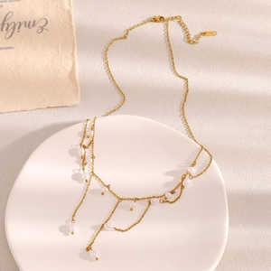 Détail d'un collier multicouche en acier doré 18K avec pampilles de perles élégantes