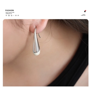 Close-up of minimalist silver water drop earrings worn by a model in a fashion style
