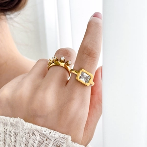 Close-up of two gold titanium rings with square and round zircon stones on a model's hand