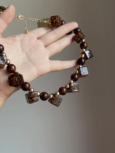 Detailed shot of leopard print acrylic cubes and dark wood beads on a vintage necklace