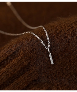 Macro shot of S925 silver bar pendant with micro-inlaid zircons on brown knit fabric