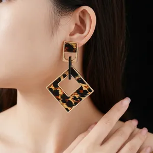 Fashionable rhombus leopard print earrings with gold metal trim worn by a model
