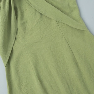 Close-up of green cotton fabric texture and precise stitching on the mini dress