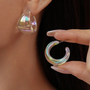 Detail of transparent C-shaped acrylic earrings with rainbow aurora finish on model