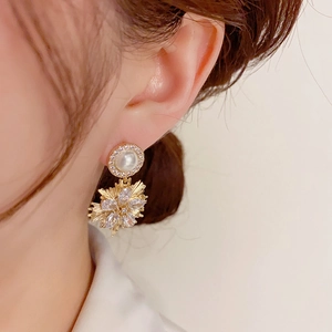 Close-up of elegant gold firework earrings with pearls and crystals on a model's ear
