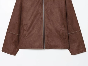 Detail der braunen Wildlederjacke mit weißen Kontrastnähten und einem Metallreißverschluss