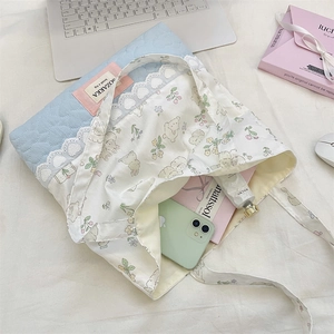 Detail of quilted light blue fabric and rabbit print tote bag with heart lace trim
