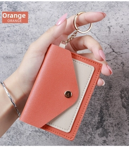 Close-up of orange leather card holder with gold keychain and snap button closure