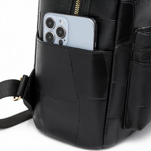 Detail of black leather backpack side pocket with golden zipper and phone storage