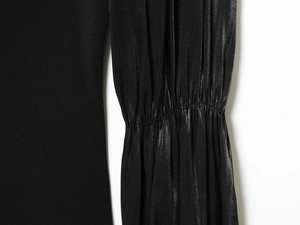 Dettaglio top nero in maglia con patchwork in raso a pieghe e finiture con bottoni