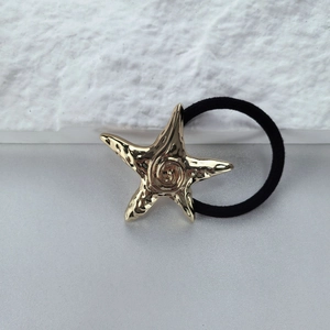 Elastic hair tie featuring a textured gold starfish charm on a minimalist background