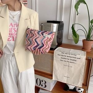 Detail view of the colorful rainbow knit texture and woven label on a canvas makeup bag