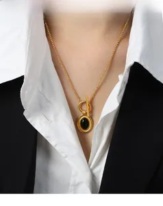Détail du collier doré avec pendentif ovale en agate noire et fermoir à bascule en T moderne