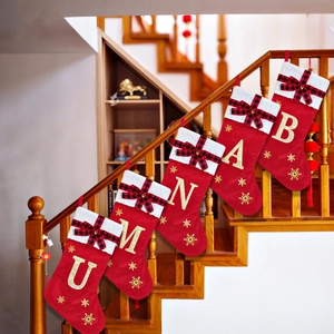 Large red Christmas stockings with gold embroidered letters on a wooden staircase