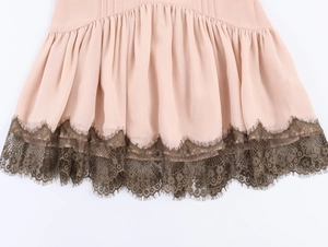Dettaglio dell'orlo in chiffon rosa con pizzo ciglia marrone scuro e design a pieghe