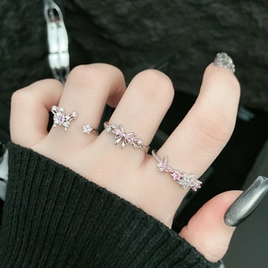 Detail of silver rings set featuring pink butterfly and bow design on finger